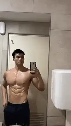 Muscular man flexing in bathroom mirror