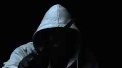 hooded figure holding knife in dark
