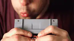 Man blowing into NES cartridge