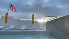 American flag waving over pool at sunset