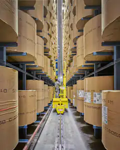 Warehouse worker on yellow lift between paper rolls