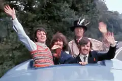 The Beatles waving from a car