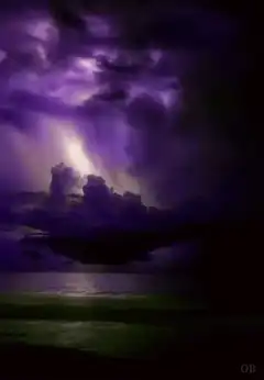 Purple storm clouds over ocean with lightning