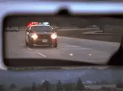 Police cars chasing in rearview mirror