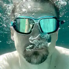 Man underwater with goggles blowing bubbles