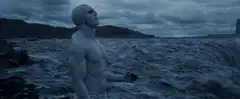 Bald muscular man standing by turbulent sea