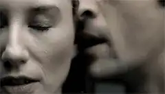 man whispering in woman's ear