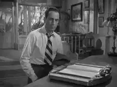 Humphrey Bogart adjusting his tie