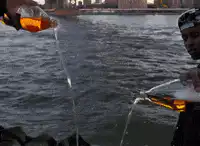 Two people pouring beer into the river
