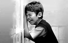 Crying boy leaning against wall