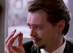 Steve Buscemi holding a small object