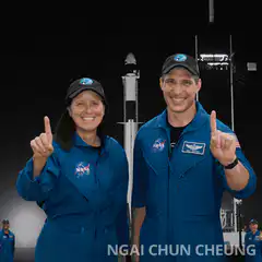 NASA astronauts pointing up at rocket