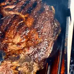 Grilled steak flambéed on barbecue