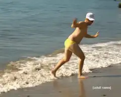 Man in yellow speedo running on beach