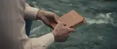Man holding a book over water