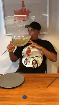 man drinks from giant wine glass