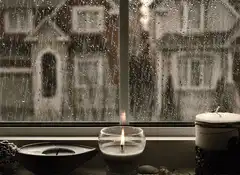 Candle burning on a rainy window sill