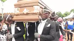 Men dancing while carrying a coffin