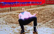 Man in pink shirt squatting in mud