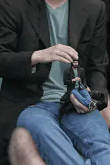 man holding tiny man on hand
