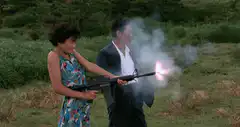Woman firing a rifle in a field