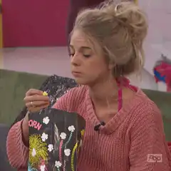 Blonde woman eating popcorn and looking shocked