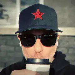 Man in cap and sunglasses drinking coffee