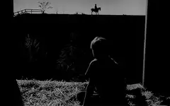 Silhouette of person watching rider on hill