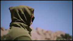 Hooded figure sees moon in daylight