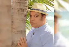 Jimmy Fallon in straw hat by palm tree