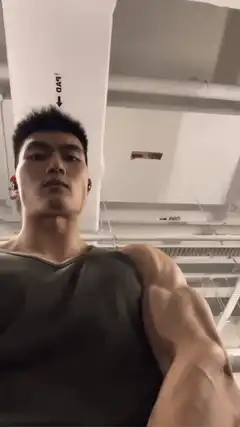 Man flexing muscular arm in gym