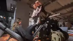Woman doing leg press with two kids on the weight