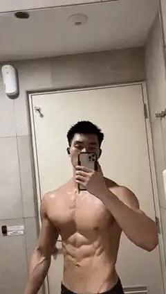 Muscular man flexing abs in bathroom mirror
