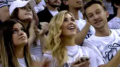 Blonde woman pointing at camera in crowd