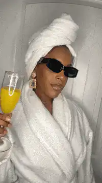 Woman in robe and sunglasses with mimosa