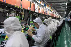 Factory workers in clean suits assembling electronics