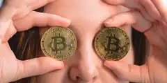 woman holding bitcoin coins over eyes
