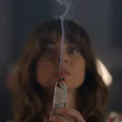 Woman smudging and fixing hair behind blinds