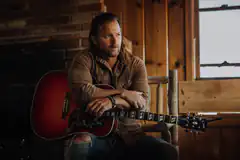 man with guitar in rustic room