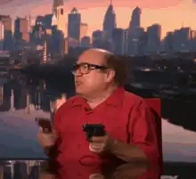Danny DeVito holding guns and pointing