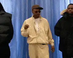 Man in beige suit dancing with text overlays