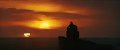 Silhouette of person on cliff at sunset