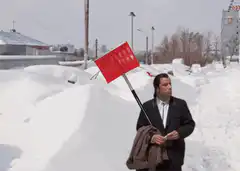 Man in suit with red shovel in snow