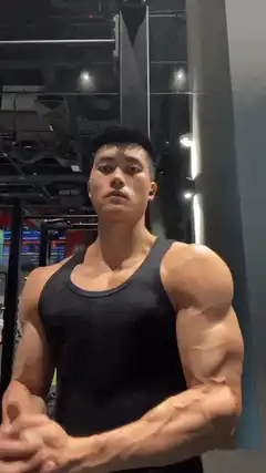 Muscular man flexing abs and arms in gym