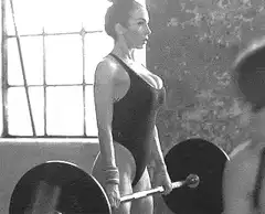 Woman deadlifting barbell in gym