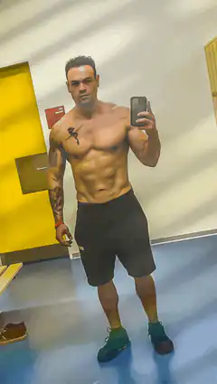 Shirtless man flexing in locker room mirror