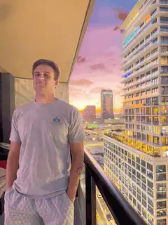 Man on balcony with sunset city view