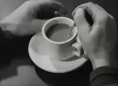 Hands stirring coffee in black and white