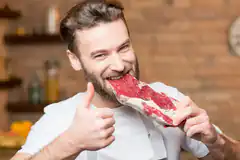 Man eating raw steak with thumbs up