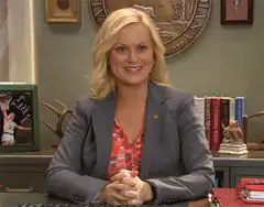 Leslie Knope smiling at desk